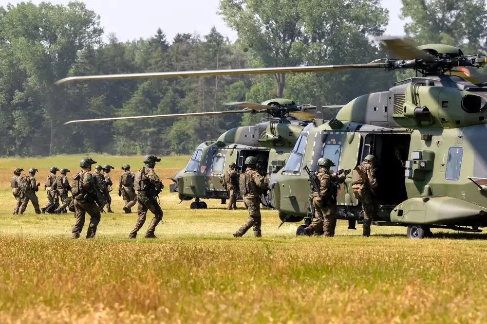 Bundeswehrsoldaten besteigen zwei NH90 Hubschrauber auf einer Wiese
