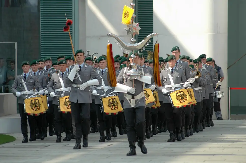 Bundeswehr-Soldaten in Uniform marschieren mit Trommeln bei einer feierlichen militärischen Zeremonie im Freien.