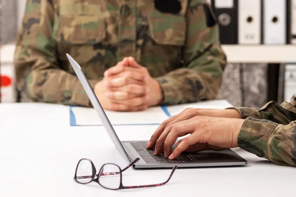Soldat im Beratungsgespräch bei der Bundeswehr Karriereberatung über Dienstgrade und Laufbahnen am Laptop.