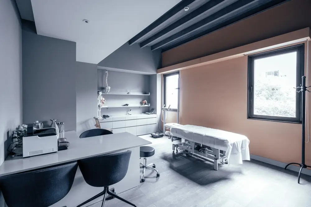 Modernes Untersuchungszimmer mit Behandlungsliege, Skelettmodell und medizinischer Ausrüstung für die Musterung.
