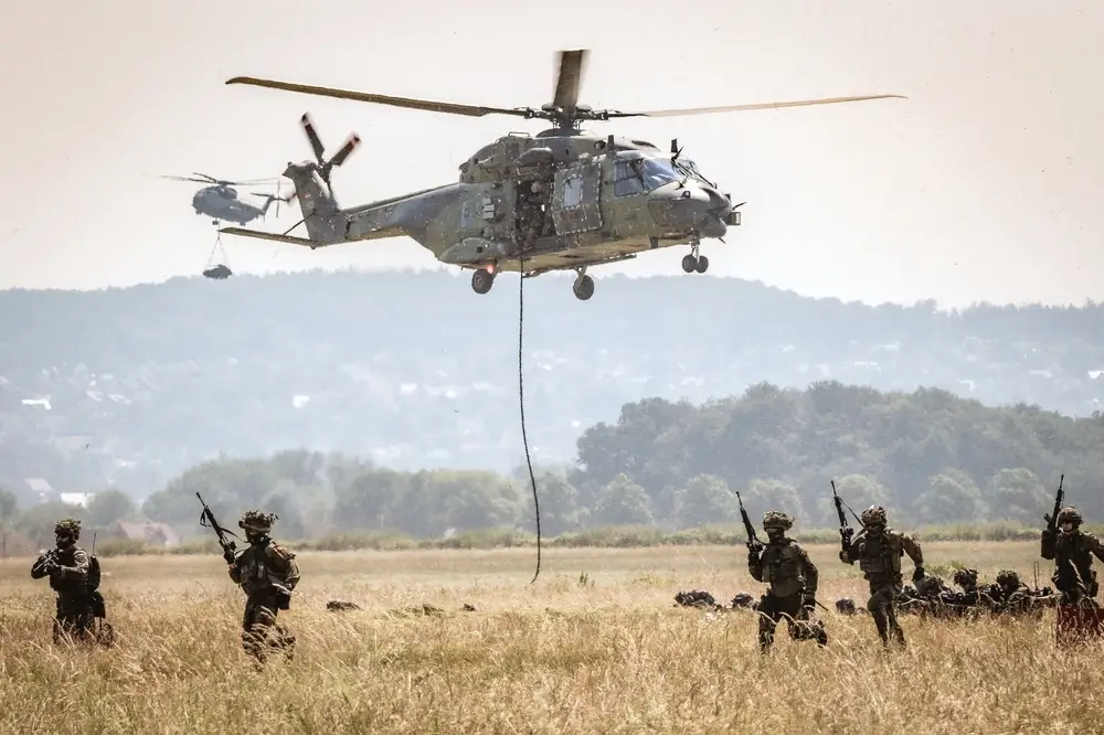 Bundeswehr-Soldaten im Feldanzug rücken bei einer Übung unter einem Hubschrauber auf einem Truppenübungsplatz vor.