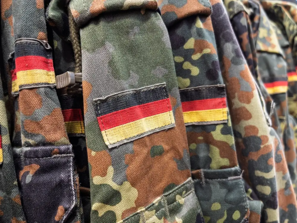 Bundeswehr-Uniformen in Flecktarn mit Deutschlandflaggen am Ärmel als Teil der militärischen Ausrüstung.