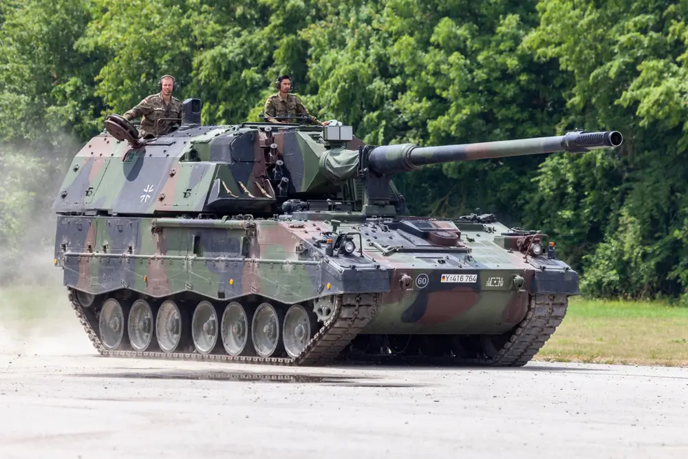 Panzerhaubitze 2000 der Bundeswehr Artillerie mit zwei Soldaten in den Luken auf einem Übungsgelände.
