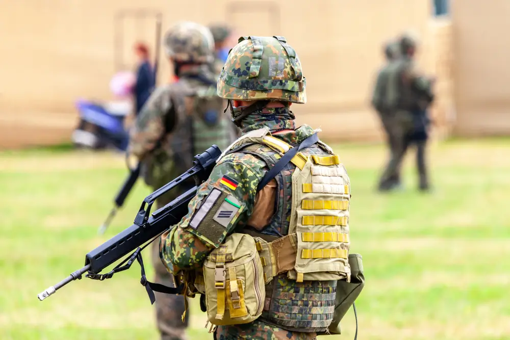 Junger Rekrut der Bundeswehr in Uniform und Schutzausrüstung mit Gewehr während der militärischen Grundausbildung.