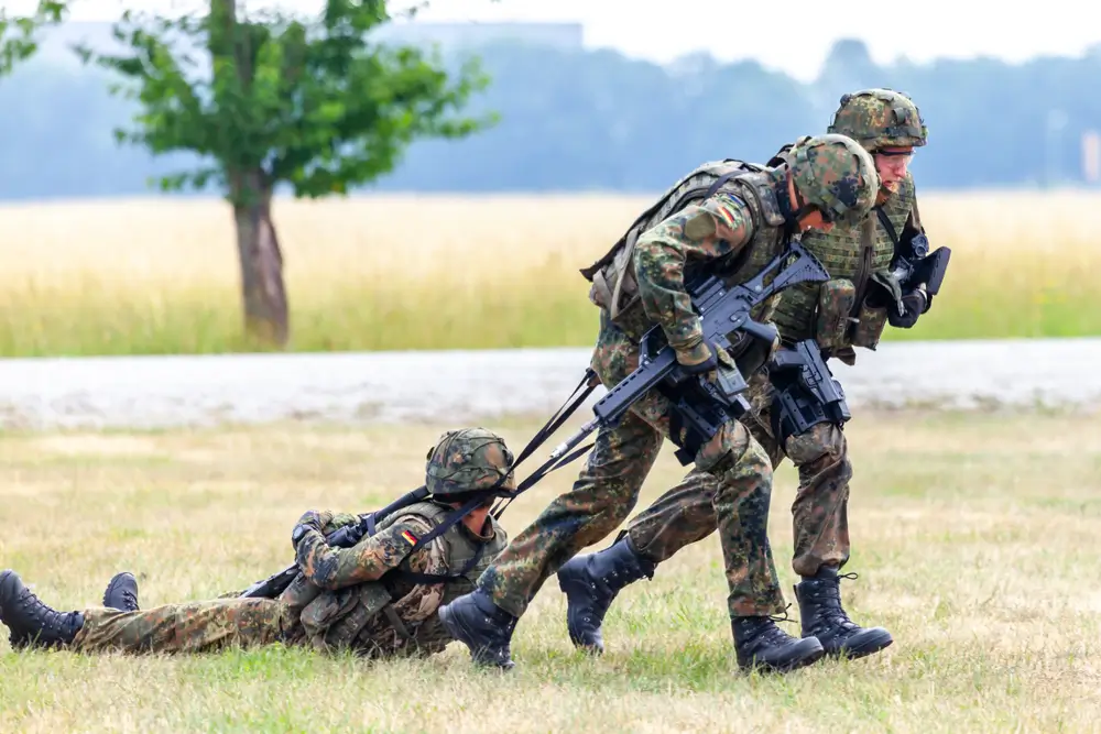 Bundeswehr-Soldaten trainieren die Bergung eines Kameraden während einer Geländeausbildung im freien Feld.
