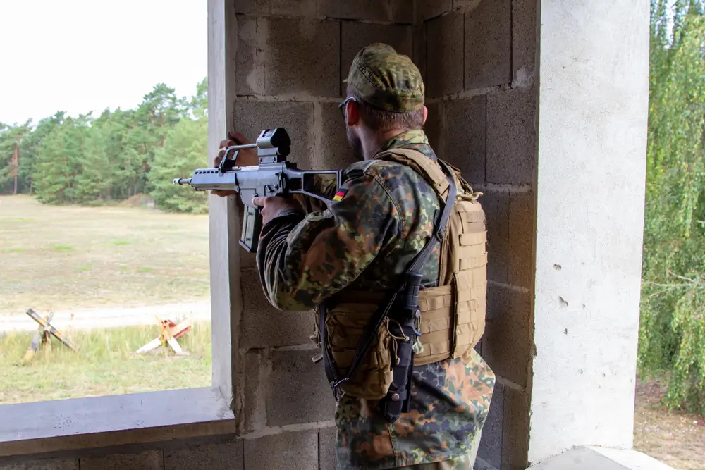 Bundeswehr-Rekrut zielt während der Grundausbildung mit seinem Gewehr aus dem Fenster eines Übungsgebäudes.