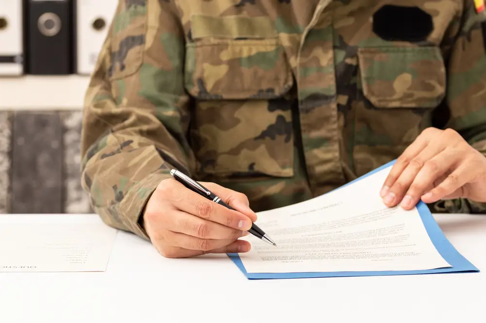 Soldat in Uniform im Karriereberatungsbüro der Bundeswehr unterzeichnet Unterlagen zur Personalrekrutierung.