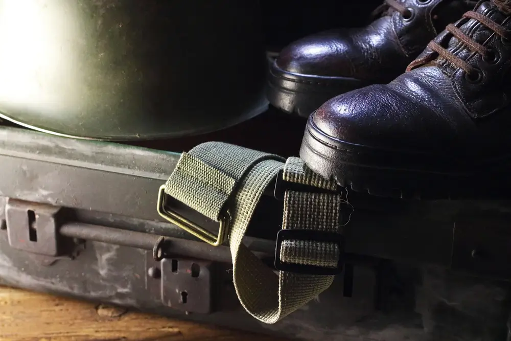 Schwarze Soldatenstiefel, Helm und Gurt auf einem Bundeswehr-Spind als Teil der dienstlichen Ausrüstung.