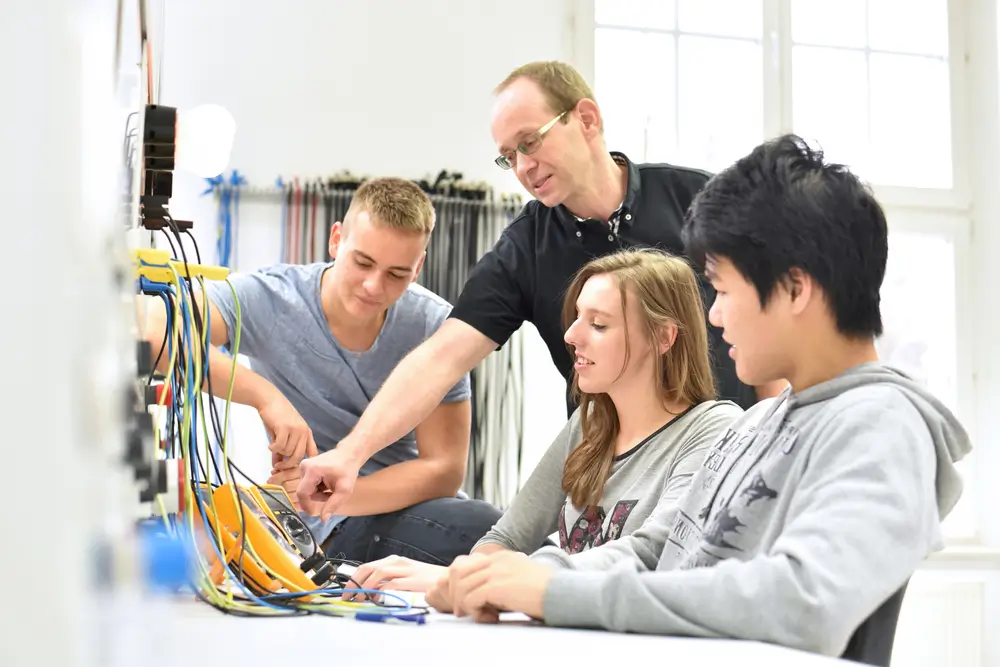 Bundeswehr Azubis in technischer Ausbildung arbeiten mit ihrem Ausbilder in einer Werkstatt an Elektronik-Komponenten.