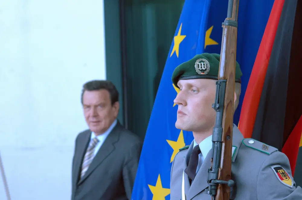 Bundeswehrsoldat in Uniform vor der Bundesflagge als Zeichen für den freiwilligen Wehrdienst und Patriotismus.