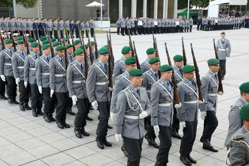 Soldaten der Bundeswehr in Uniform bei einer Zeremonie der deutschen Armee mit Gewehren auf einem Kasernenhof.