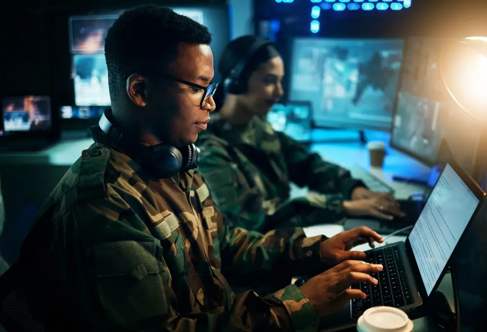 Soldaten arbeiten konzentriert an Laptops in einem modernen militärischen Kontrollzentrum einer Bundeswehr-Kaserne.