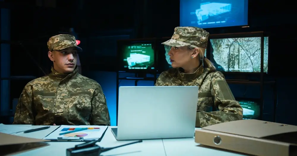 Soldaten der Bundeswehr im Büro betrachten am Schreibtisch Dokumente und Diagramme zur aktuellen Besoldung.