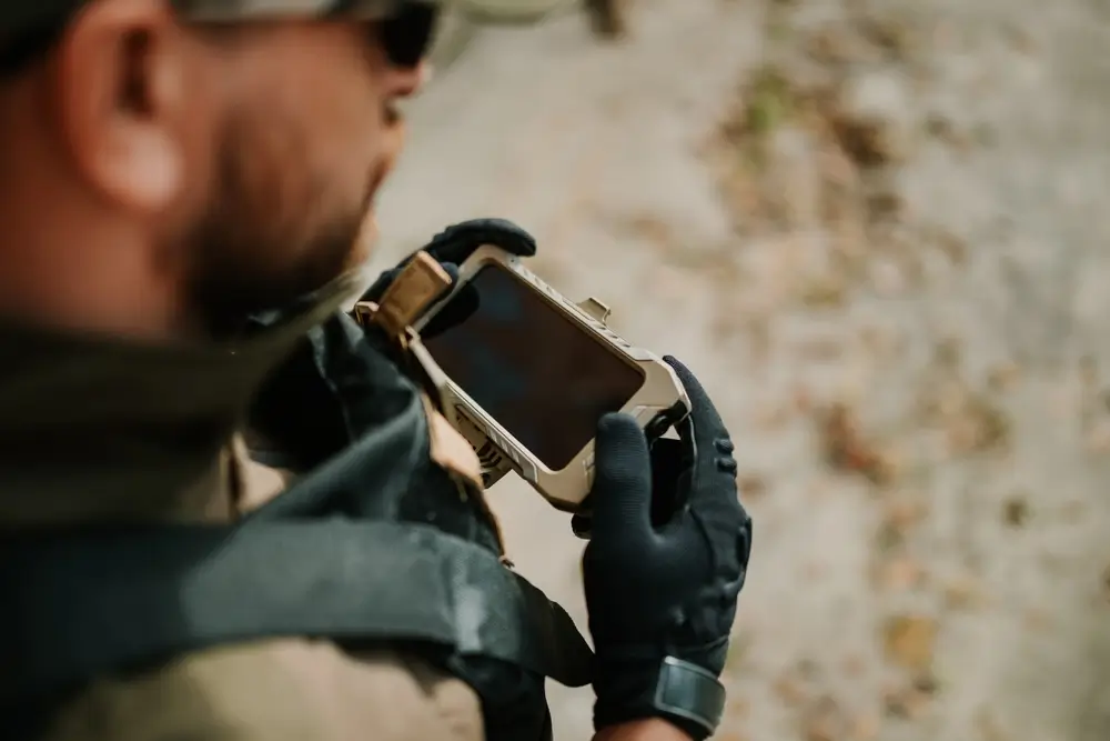 Deutsche Soldatin der Bundeswehr nutzt ein robustes Smartphone bei einer Übung im Gelände.