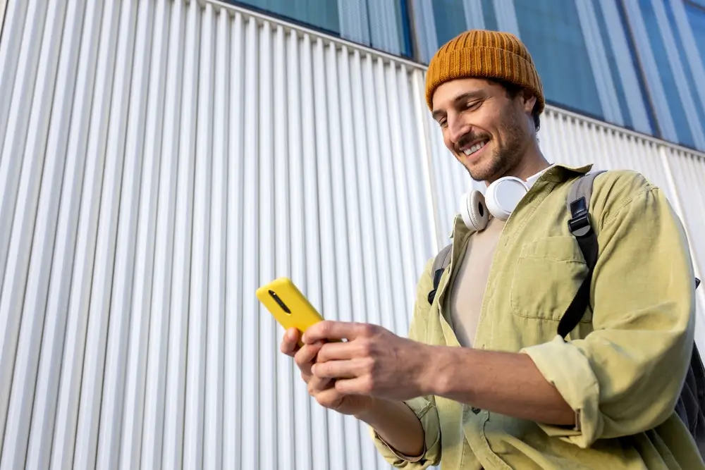 Ein lächelnder junger Mann füllt am Smartphone den digitalen Fragebogen zur Wehrerfassung aus.