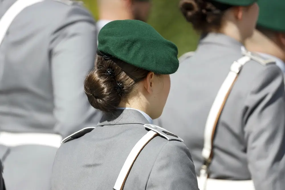 Junge deutsche Soldatin in Bundeswehr-Uniform mit grünem Barett bei einer offiziellen Zeremonie.