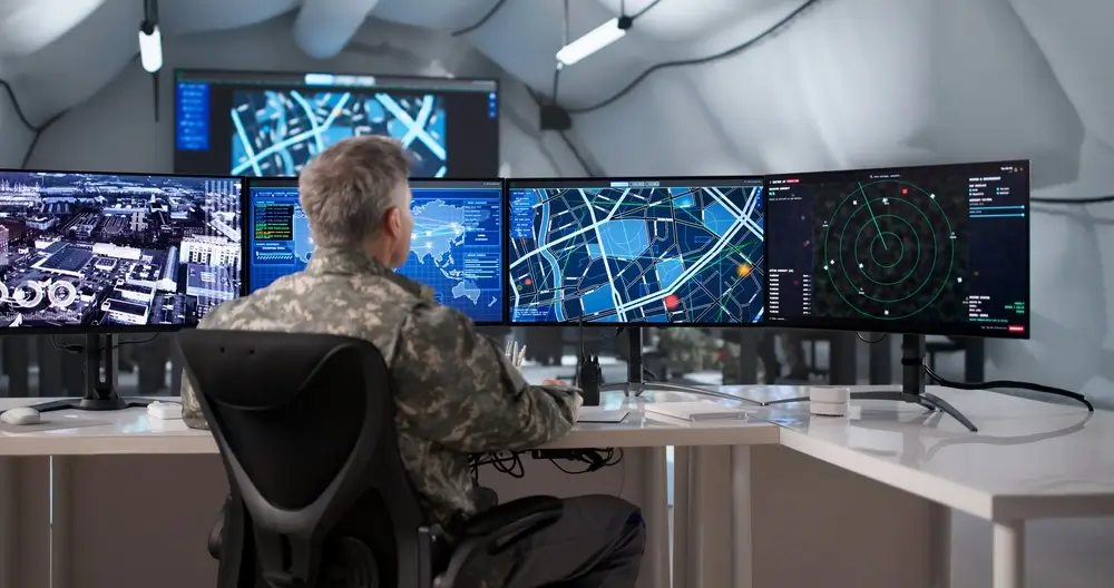 Bundeswehr-Soldat an einem modernen Computerarbeitsplatz mit mehreren Monitoren für IT- und Cyber-Einsätze.