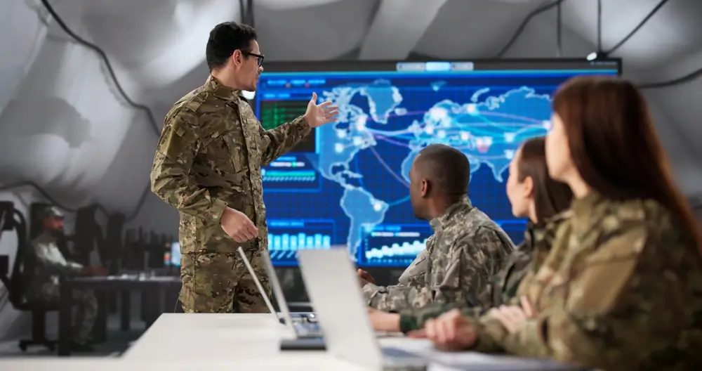 Bundeswehr-Soldaten bei einer taktischen Besprechung vor einem digitalen Lagebild in einer Kaserne.