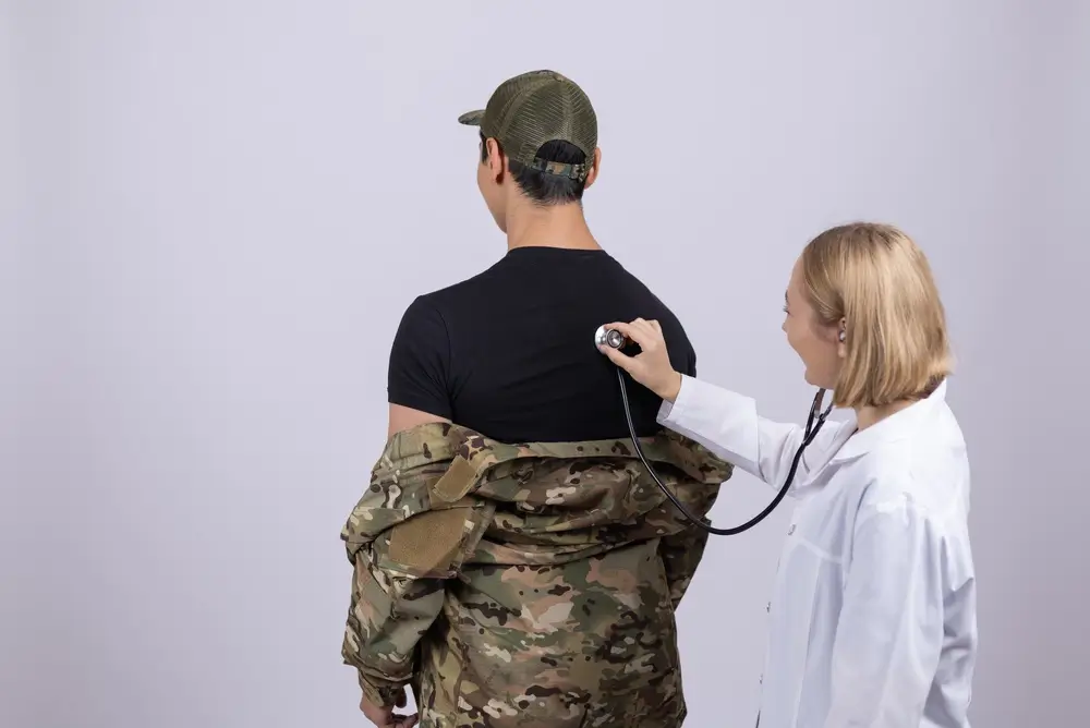 Ärztin untersucht den Rücken eines Soldaten mit einem Stethoskop bei einer medizinischen Musterung für die Bundeswehr.