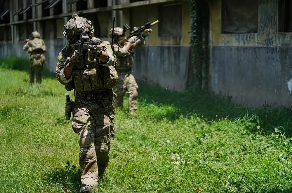 Soldaten in voller Ausrüstung bei einer taktischen Übung im Gelände während der militärischen Ausbildung.
