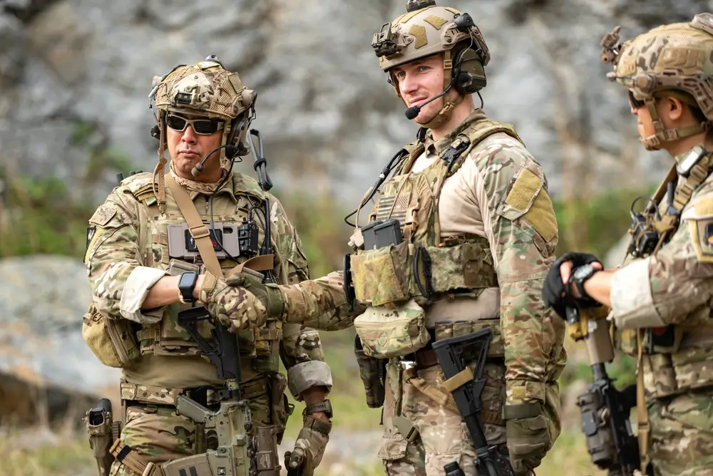 Ein Bundeswehr-Offizier übernimmt die Führung und begrüßt einen Soldaten per Handschlag im Gelände.