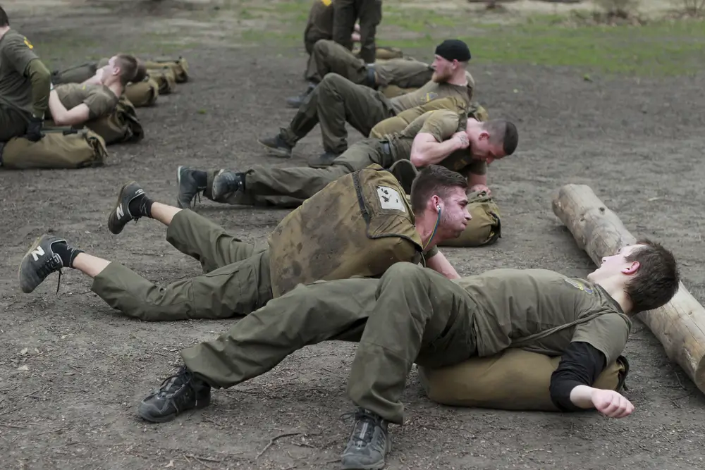 Bundeswehr-Soldaten trainieren mit Sandsäcken bei einer militärischen Übung zur Steigerung der Fitness im Gelände.